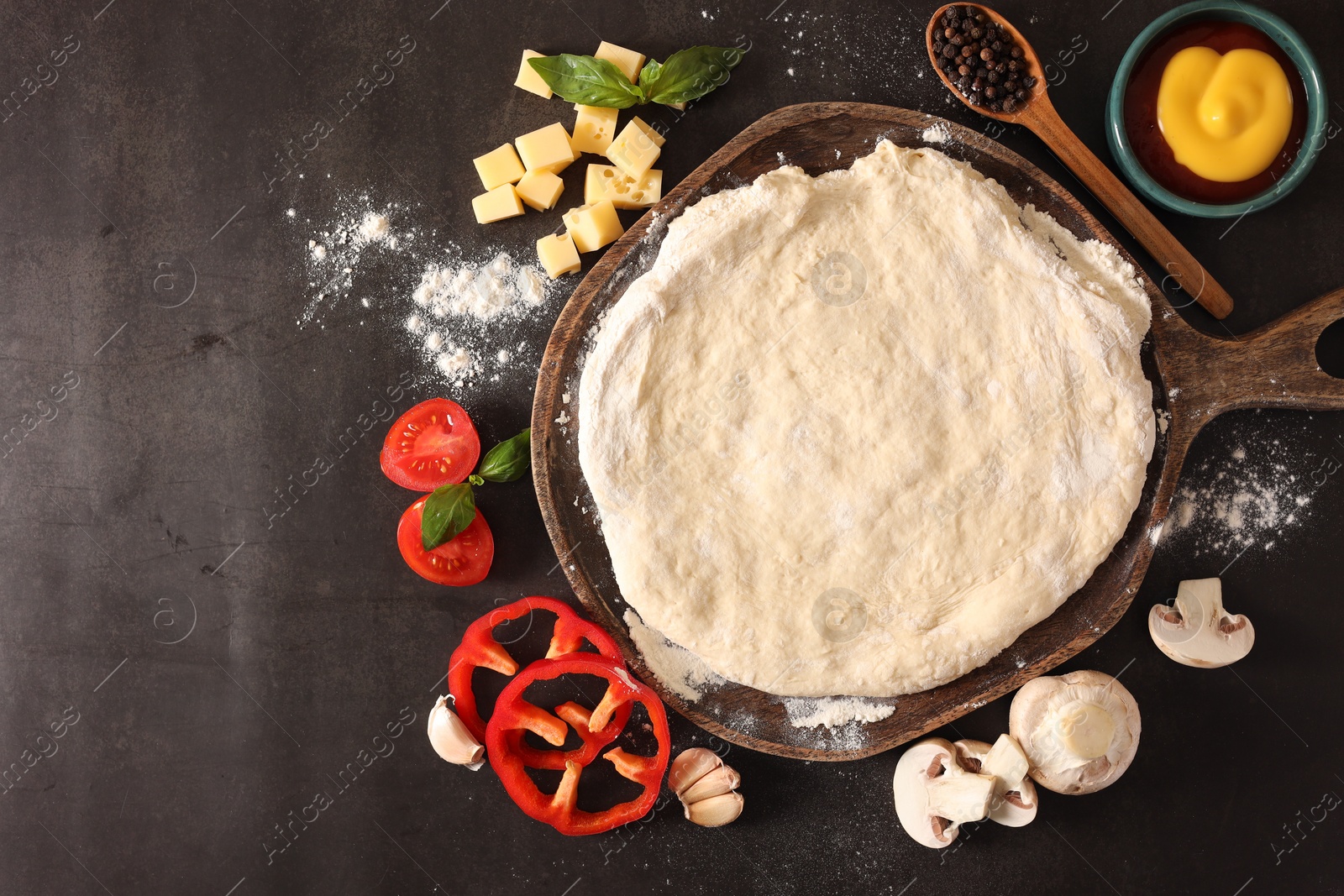 Photo of Pizza dough and products on dark table, flat lay. Space for text