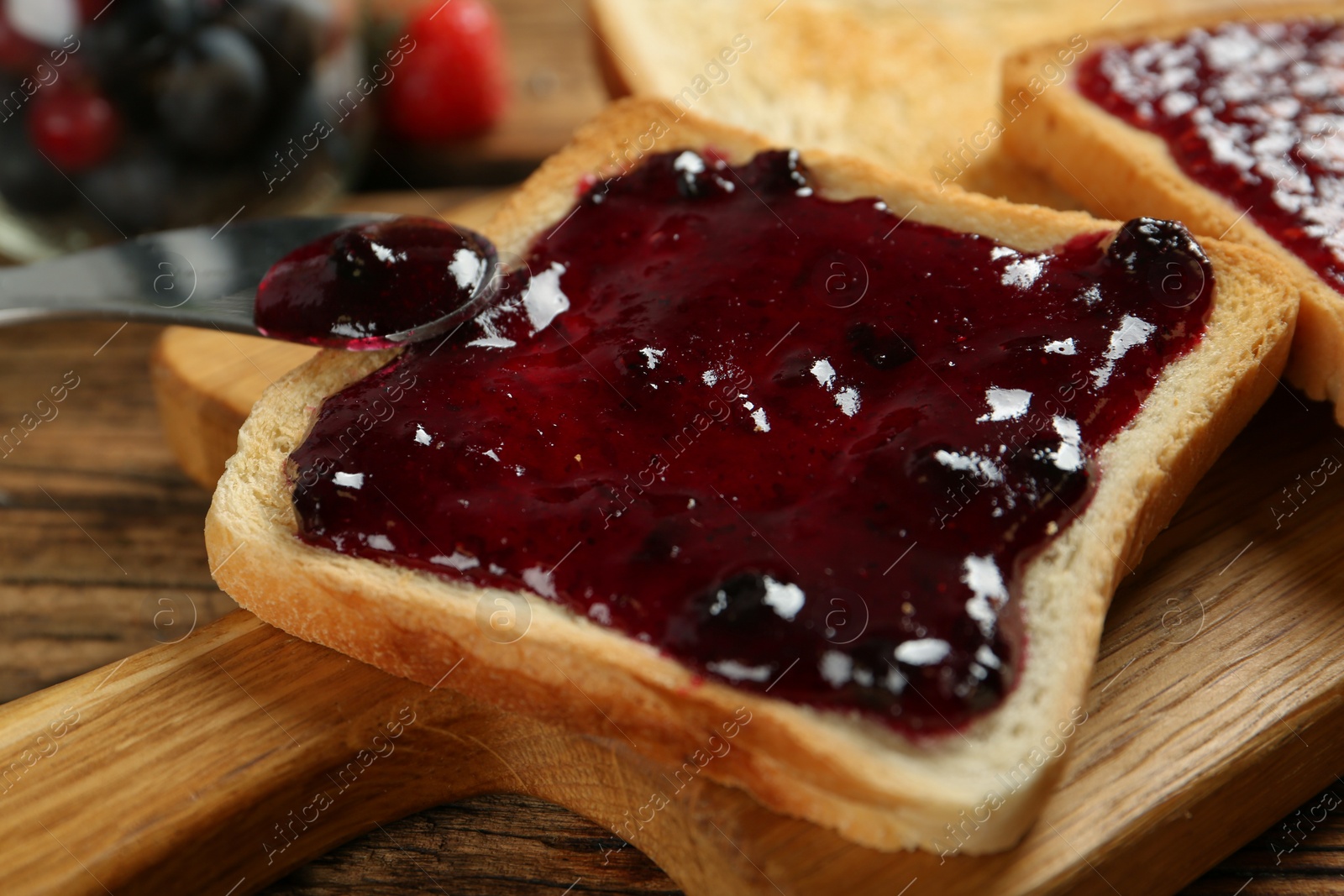 Photo of Delicious toast with jam served on wooden table, closeup