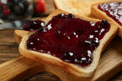 Delicious toast with jam served on wooden table, closeup