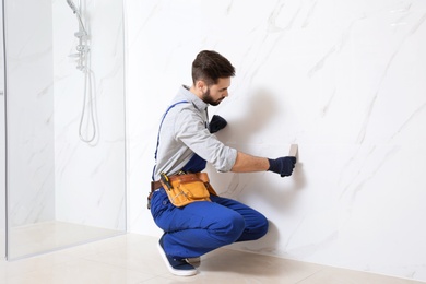 Handyman working with putty knife in bathroom. Professional construction tools