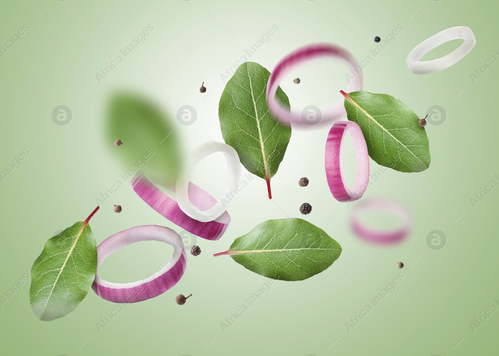 Image of Bay leaves, onion rings and black pepper grains flying on light green gradient background