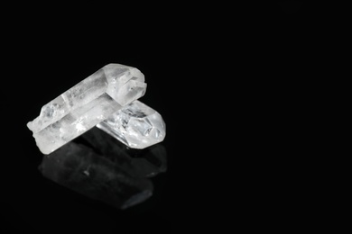 Photo of Beautiful rock crystal gemstones on black background. Space for text