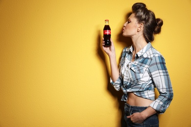 MYKOLAIV, UKRAINE - NOVEMBER 28, 2018: Young woman with bottle of Coca-Cola on color background, space for text