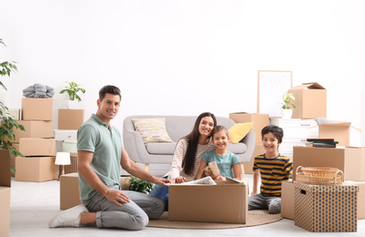 Happy family unpacking moving boxes at their new home