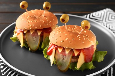 Photo of Cute monster burgers on table, closeup. Halloween party food