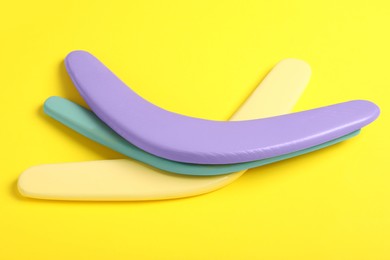 Photo of Colorful wooden boomerangs on yellow background. Outdoor activity