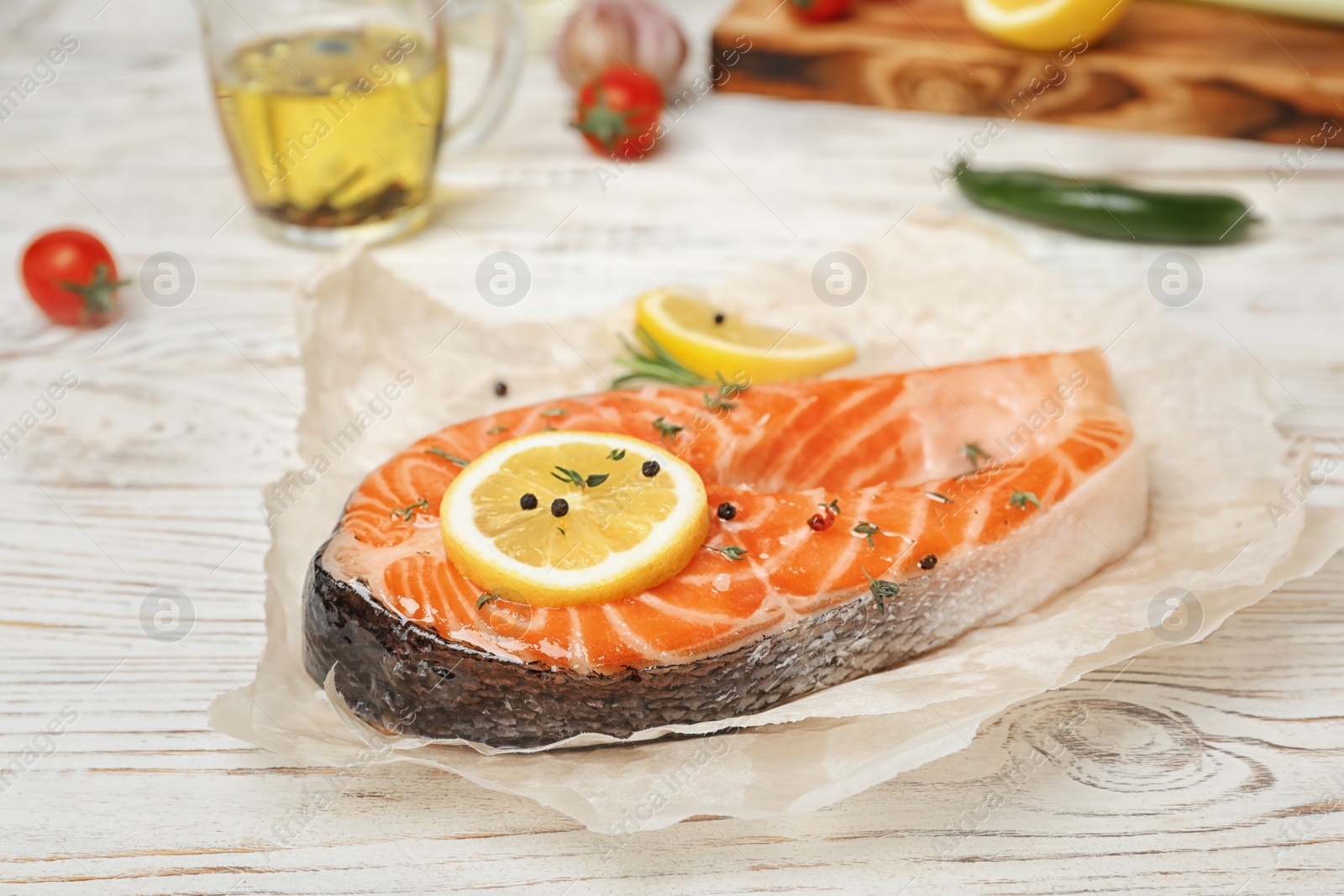 Photo of Fresh raw salmon steak with lemon and pepper on wooden table