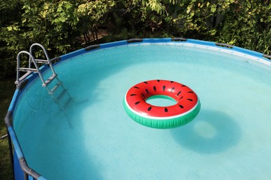 Photo of Inflatable ring floating on water in above ground swimming pool outdoors