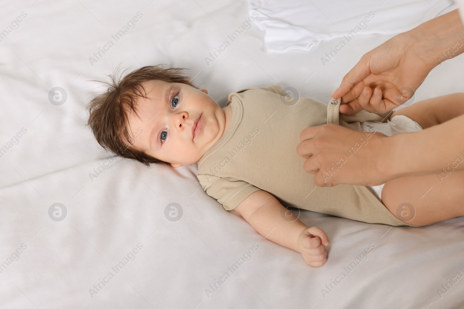 Photo of Mother putting clothes on daughter in bed, closeup