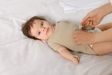 Photo of Mother putting clothes on daughter in bed, closeup