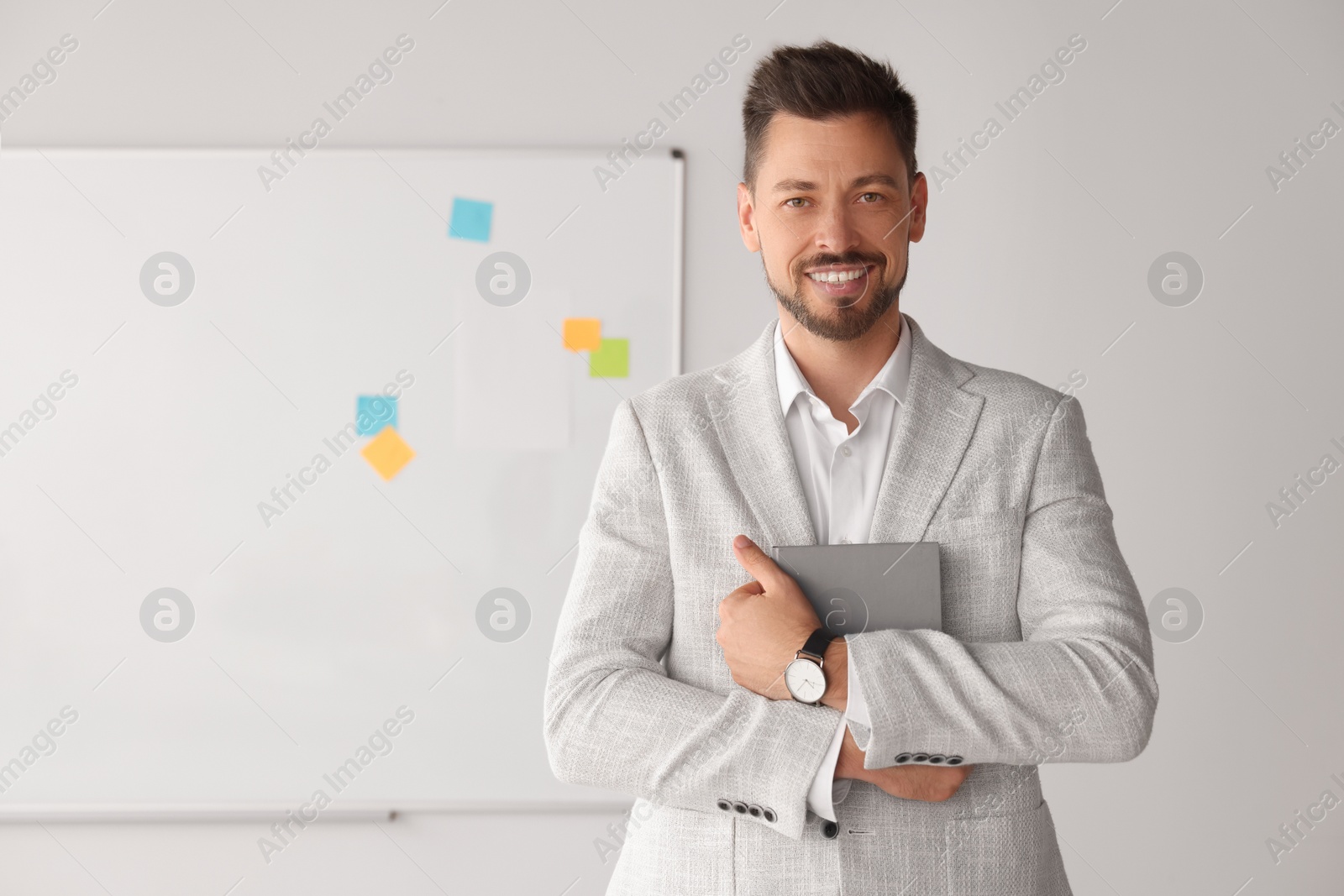 Photo of Happy teacher with book at whiteboard in classroom