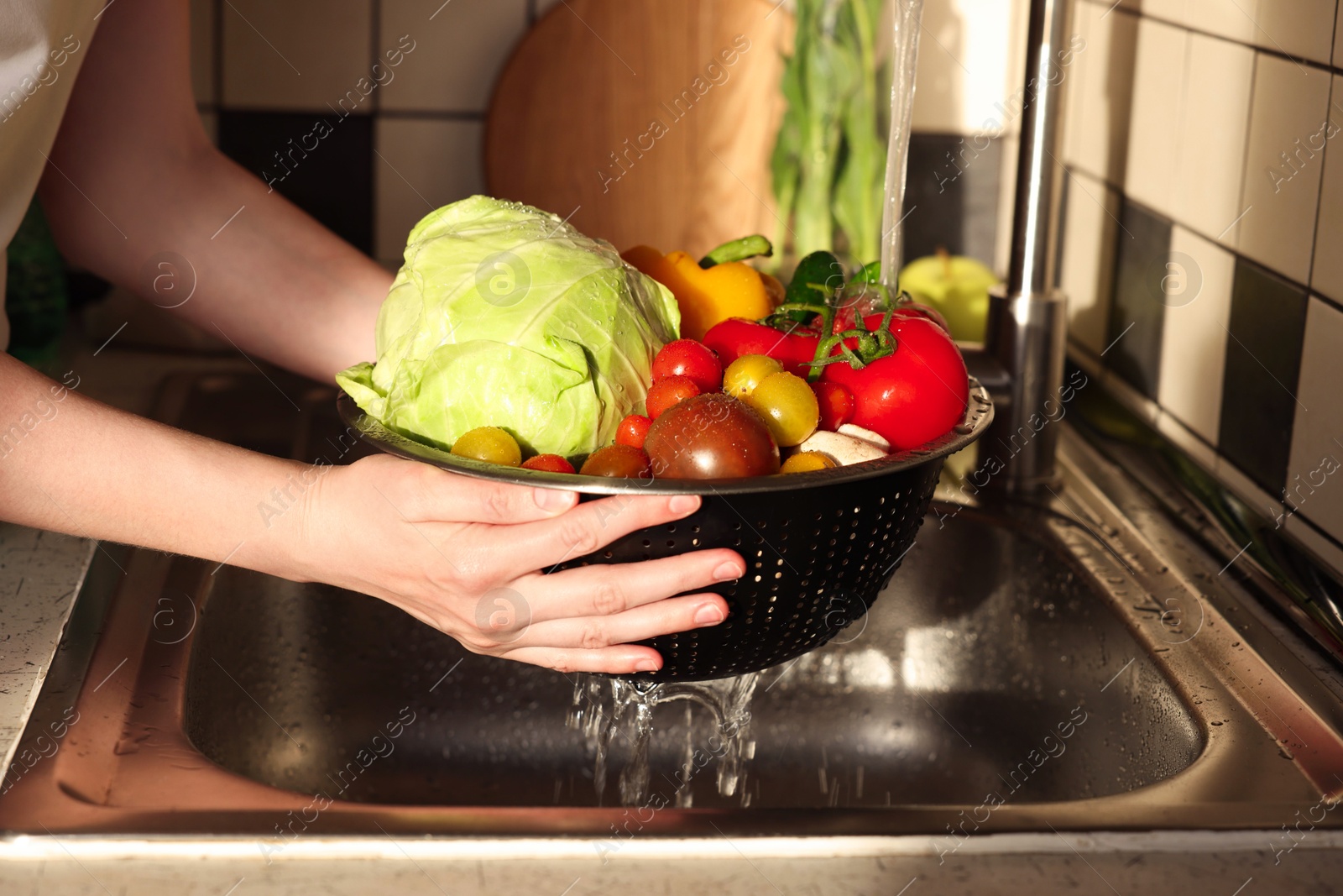 Photo of Woman washing different vegetables in metal colander, closeup