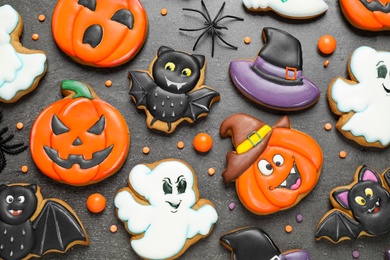 Photo of Tasty cookies and sweets for Halloween party on black table, flat lay