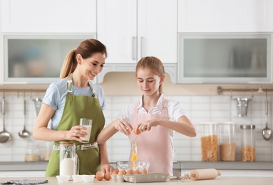 Mother and her daughter making dough at table in kitchen