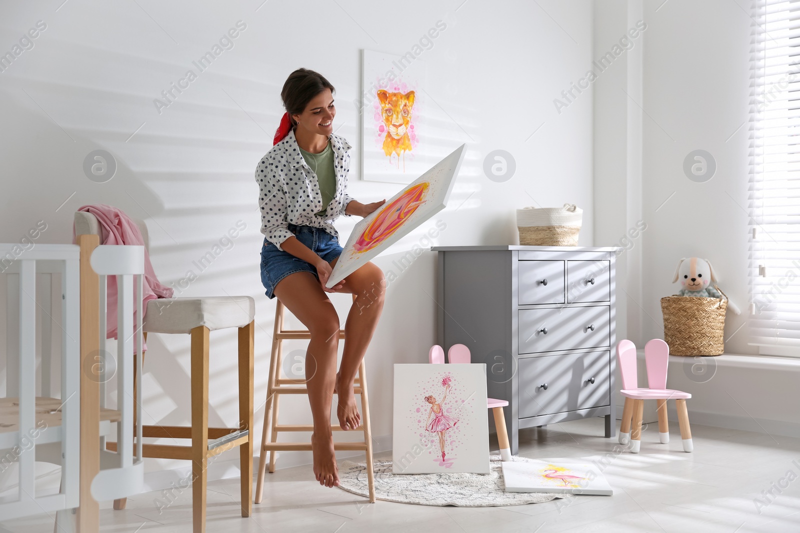 Photo of Decorator with picture on ladder in baby room. Interior design