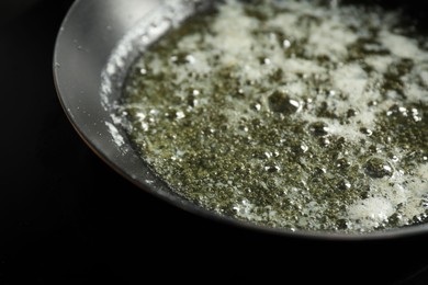 Photo of Melting butter in frying pan on black table, closeup