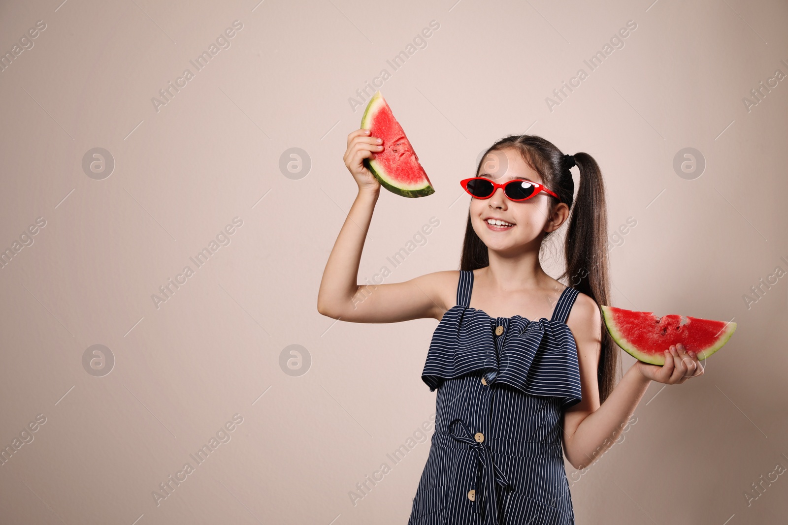 Photo of Cute little girl with watermelon on beige background. Space for text