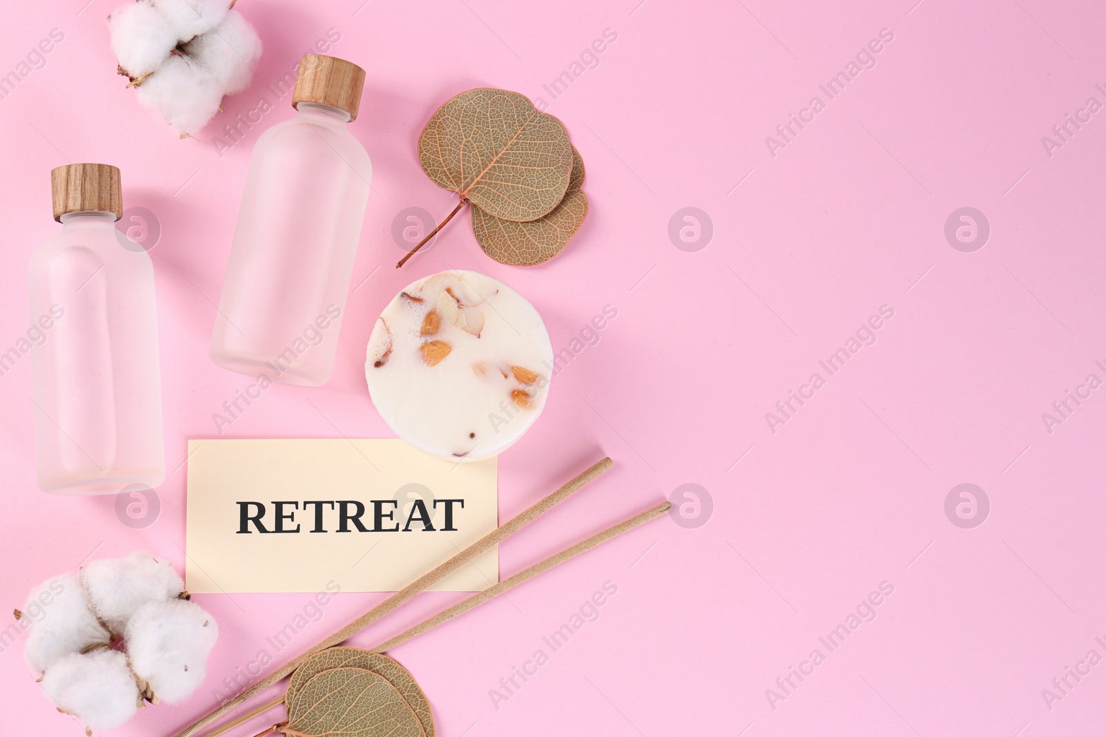 Photo of Retreat concept. Flat lay composition with card, bottles of cosmetic products and cotton flowers on pink background, space for text