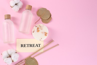 Retreat concept. Flat lay composition with card, bottles of cosmetic products and cotton flowers on pink background, space for text