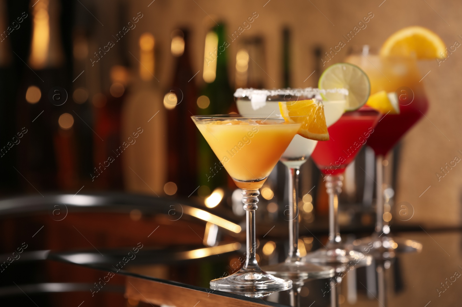 Photo of Different delicious cocktails on black table in bar. Space for text