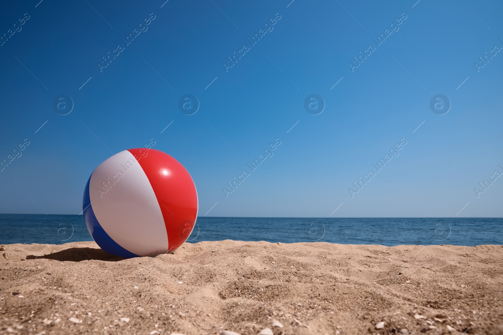 Photo of Colorful inflatable ball on sandy beach. Space for text