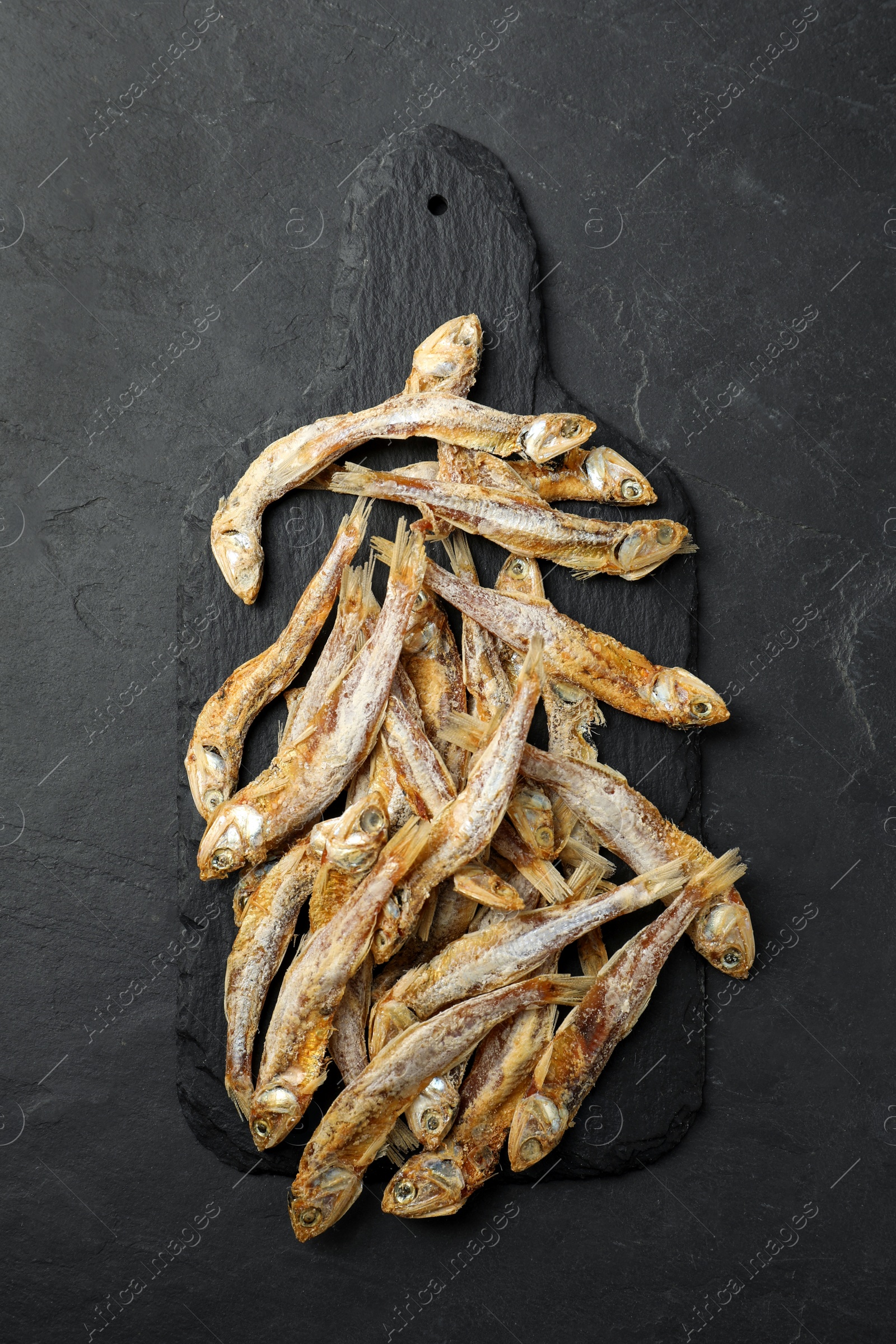 Photo of Delicious dried anchovies on black table, top view