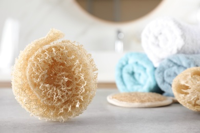 Natural loofah sponge on table in bathroom. Space for text