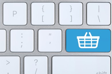 Image of Online store purchase. Light blue button with shopping basket on computer keyboard, top view