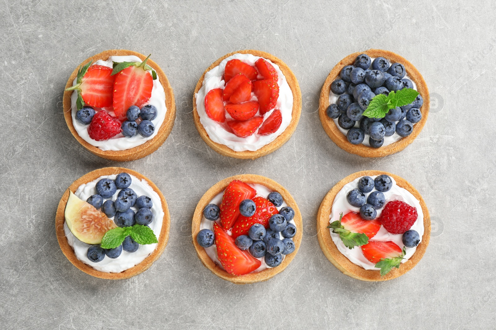 Photo of Delicious sweet pastries with berries on grey table, flat lay