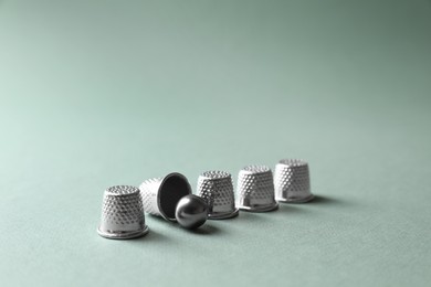 Photo of Metal thimbles and ball on pale olive background. Thimblerig game
