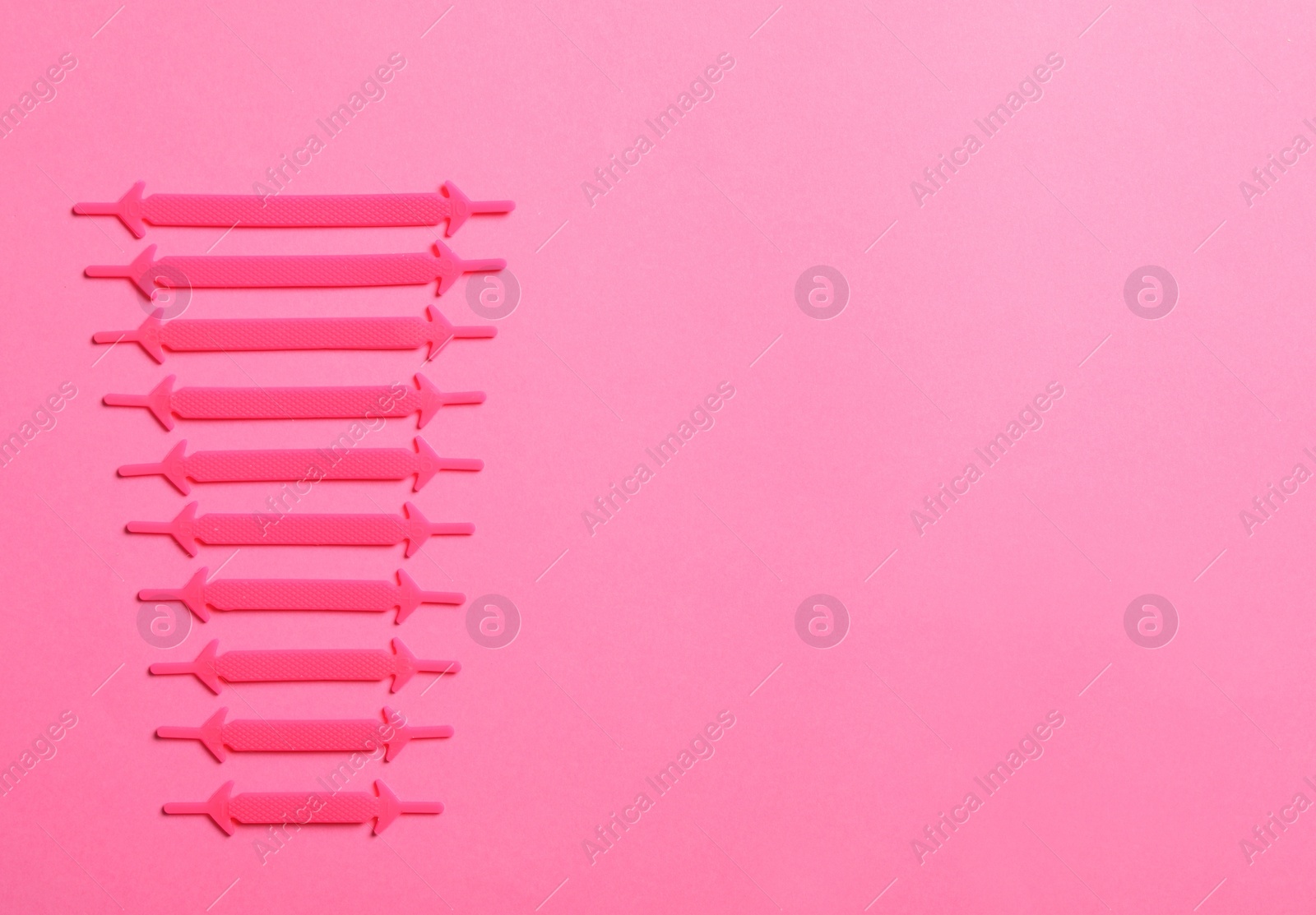 Photo of Silicone shoelaces on pink background, flat lay. Space for text