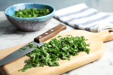 Photo of Wooden board with chopped parsley and knife on table