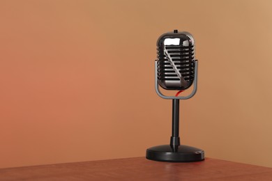 Photo of Vintage microphone on table against color background, space for text. Sound recording and reinforcement