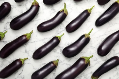 Photo of Raw ripe eggplants on white marble table, flat lay