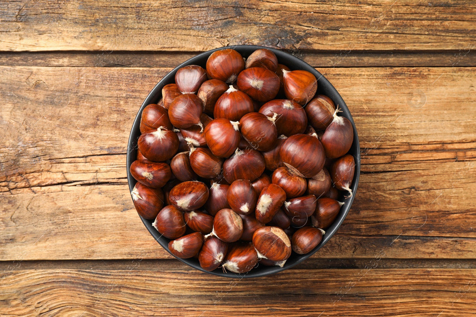 Photo of Fresh sweet edible chestnuts on wooden table, top view