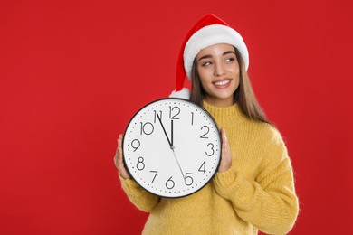 Photo of Woman in Santa hat with clock on red background. New Year countdown
