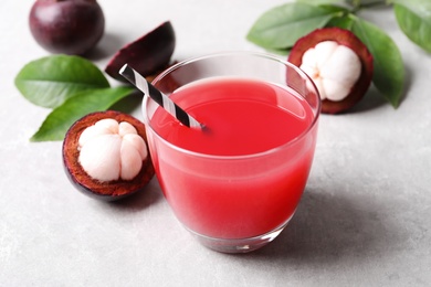 Photo of Delicious fresh mangosteen juice in glass on light grey table