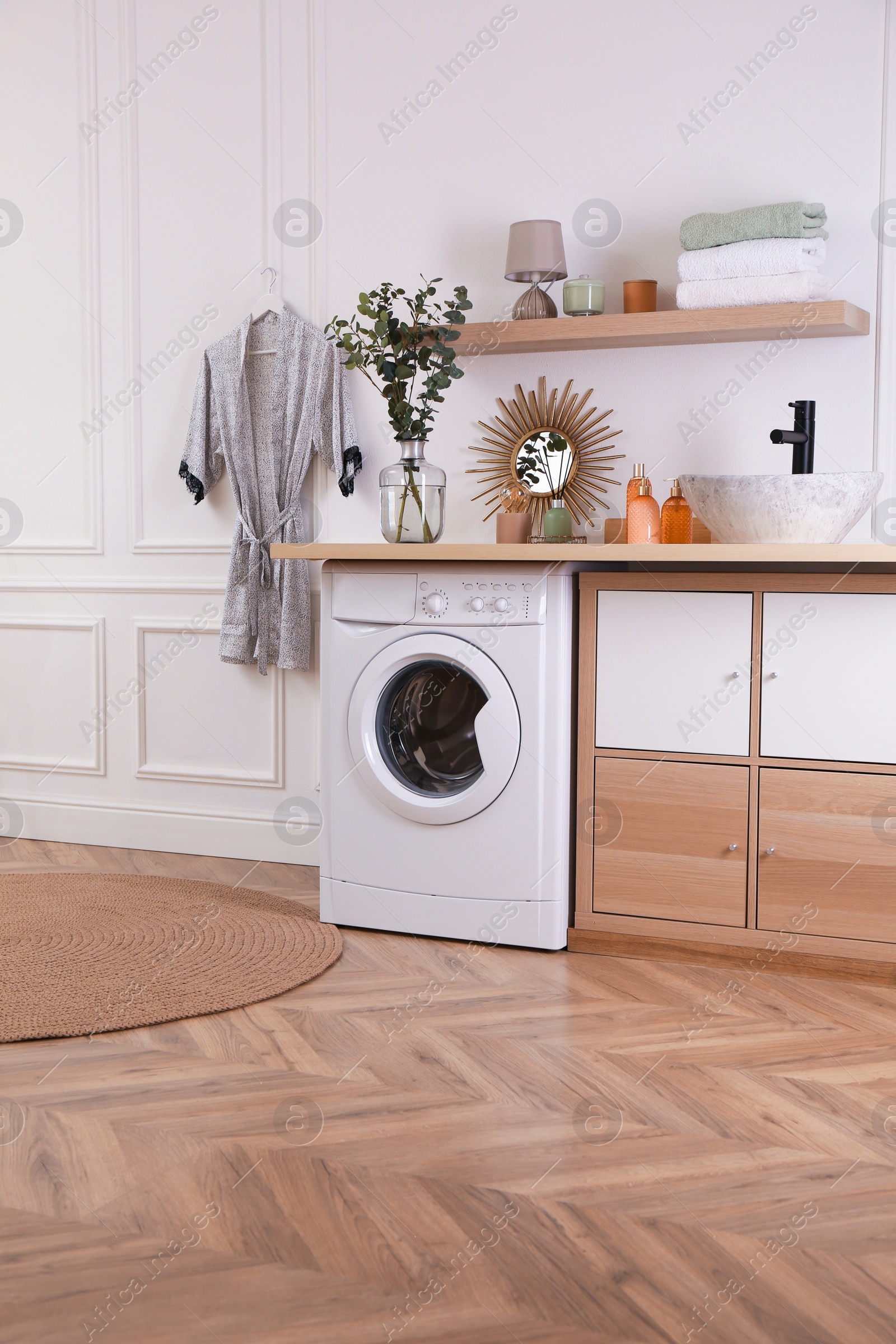 Photo of Laundry room interior with modern washing machine and stylish vessel sink on countertop