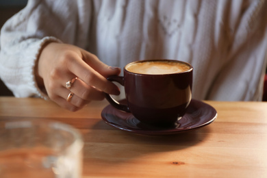 Photo of Woman with aromatic coffee at table in cafe, closeup