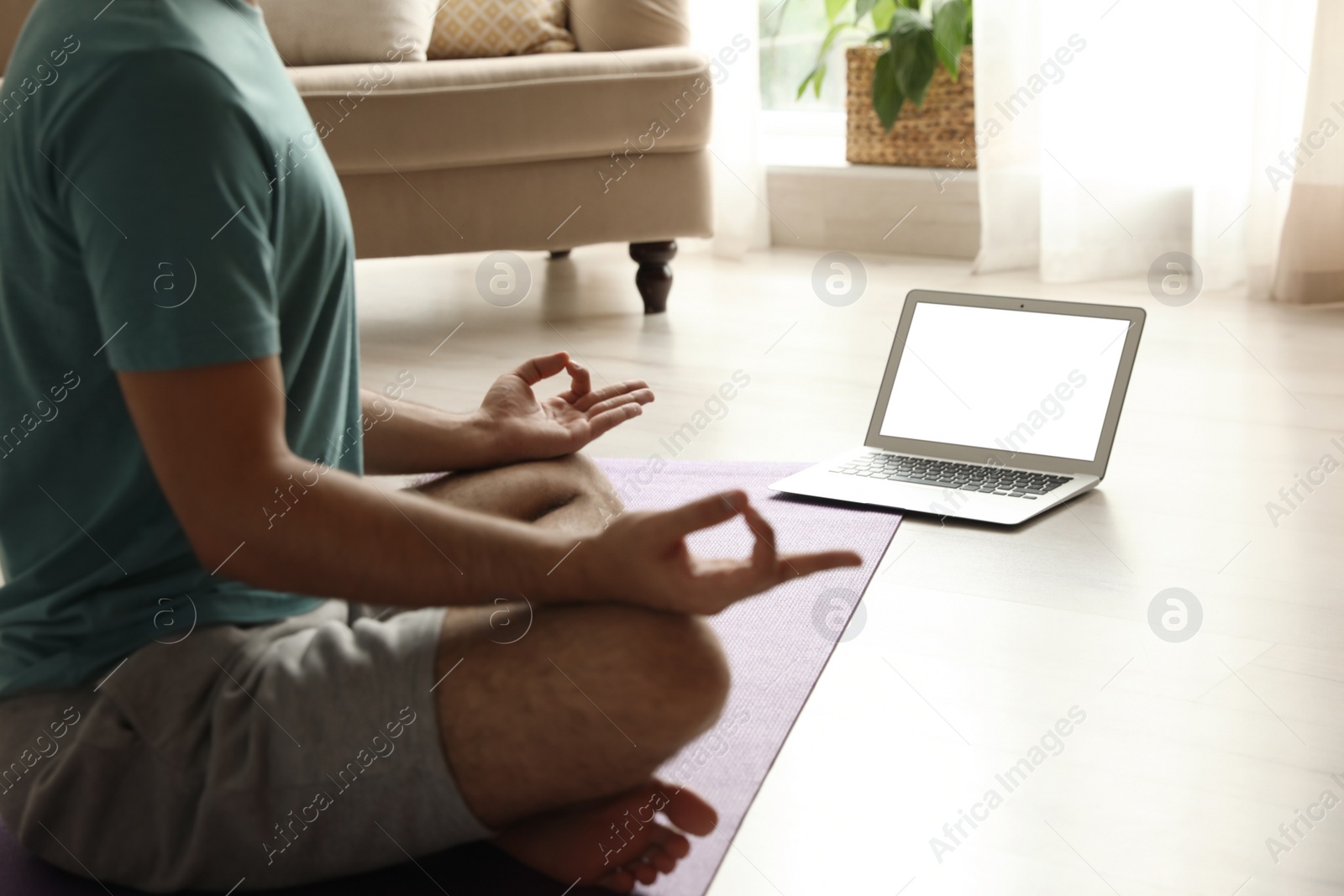 Photo of Man practicing yoga while watching online class at home during coronavirus pandemic, closeup. Social distancing