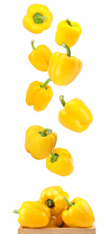 Whole yellow bell peppers falling into wooden crate on white background