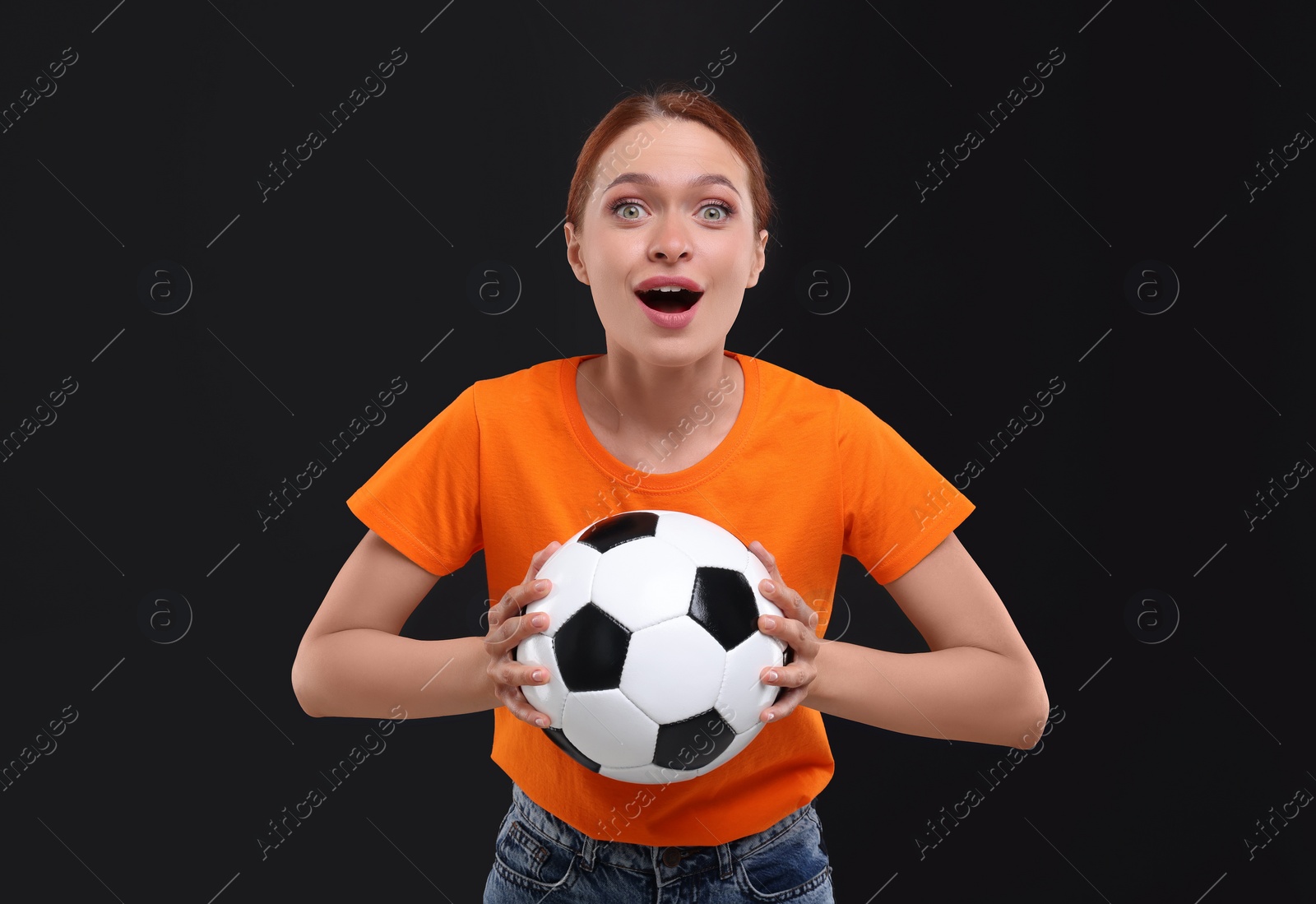 Photo of Emotional fan holding football ball on black background