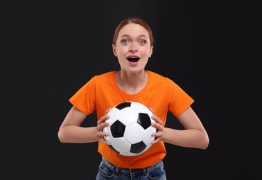 Emotional fan holding football ball on black background
