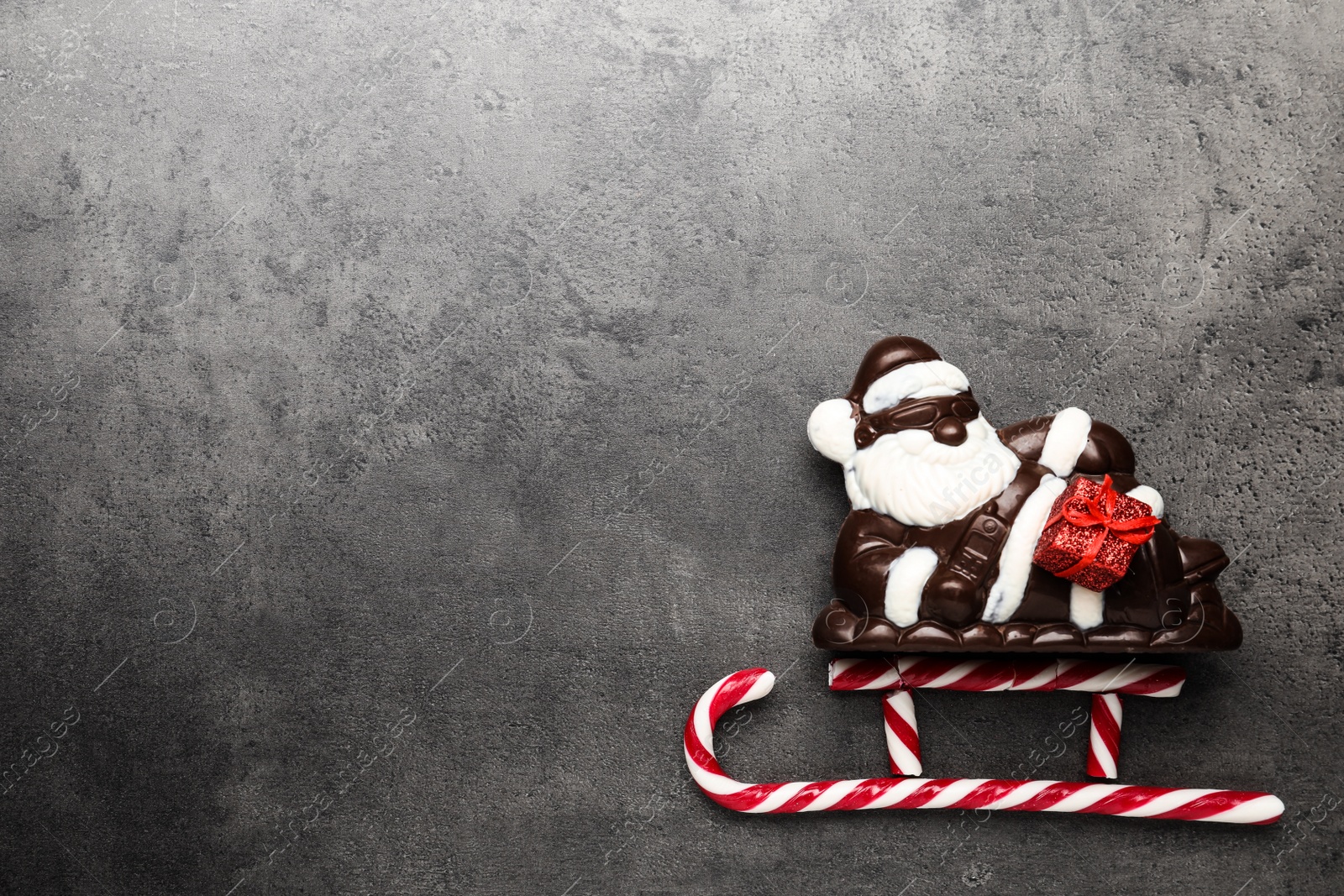 Photo of Flat lay composition with Santa Claus and candy canes on grey table