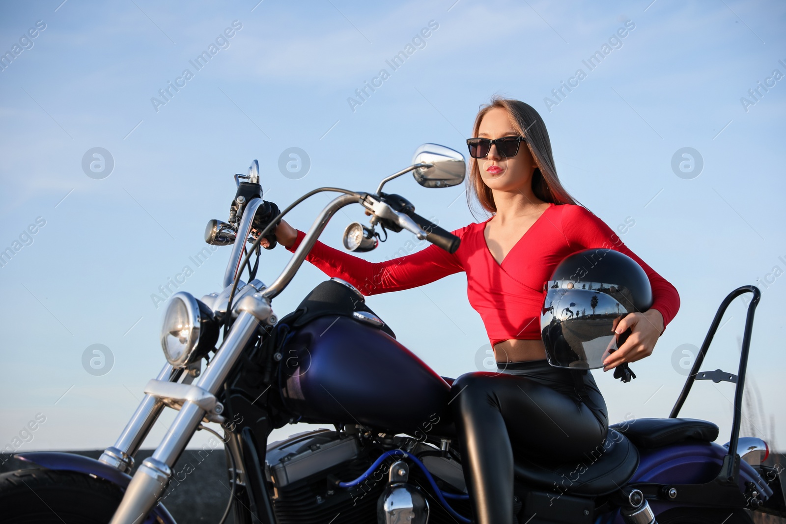 Photo of Beautiful young woman with helmet sitting on motorcycle outdoors