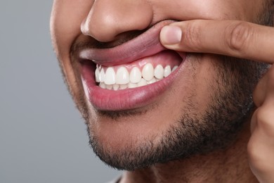 Photo of Man showing healthy gums on grey background, closeup