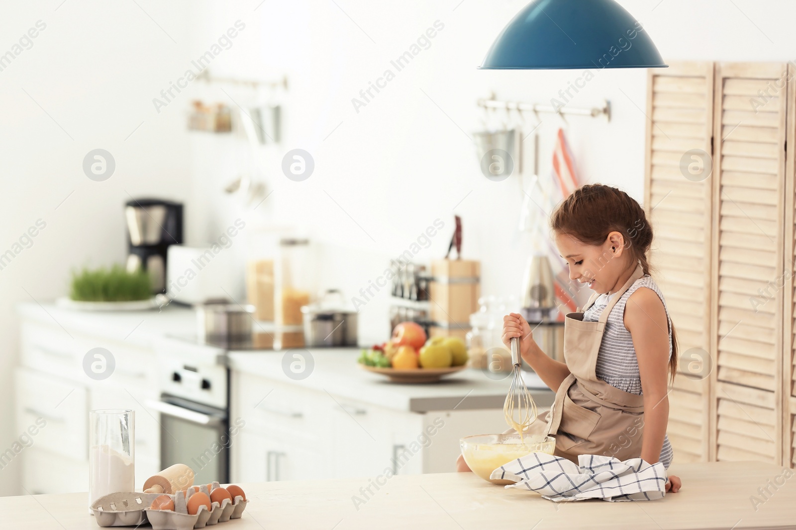 Photo of Little girl making dough at table in kitchen