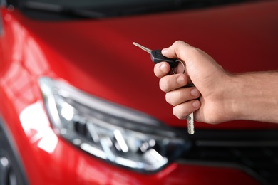 Man with car key near new auto, closeup