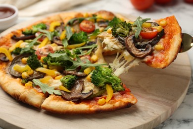 Photo of Taking piece of delicious vegetarian pizza at table, closeup