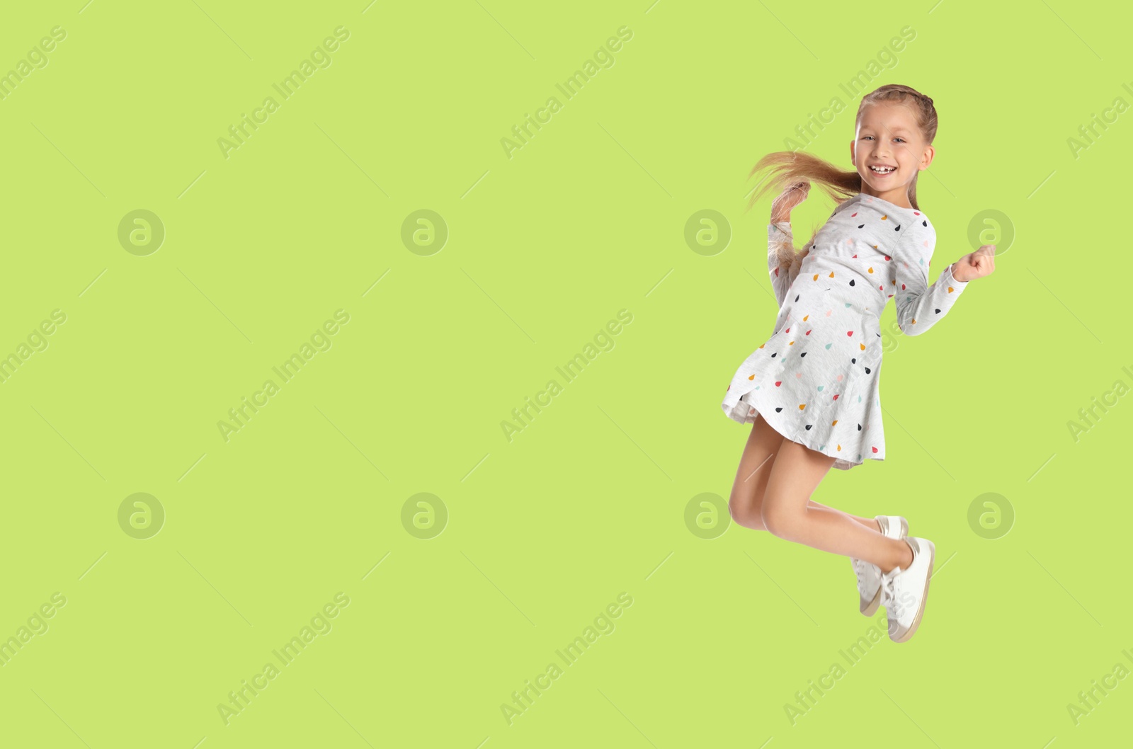 Image of Cute girl jumping on yellowish green background, space for text